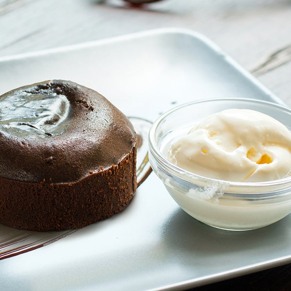 Tortino di cioccolato su piatto bianco e ciotola di panna accanto