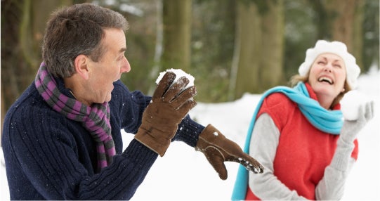 Uomo e donna che giocano con palle di neve in un bosco