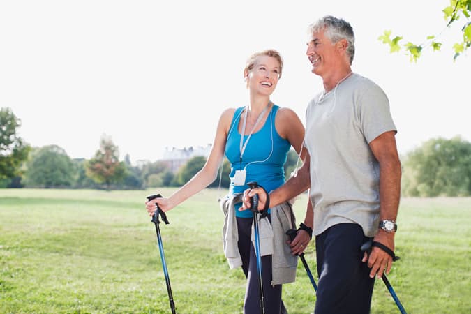 Uomo e donna sorridenti che fanno nordic walking all'aria aperta